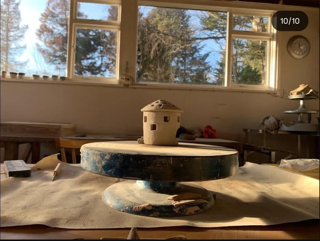 Small clay dome house model on a pottery wheel in a sunlit Findhorn studio